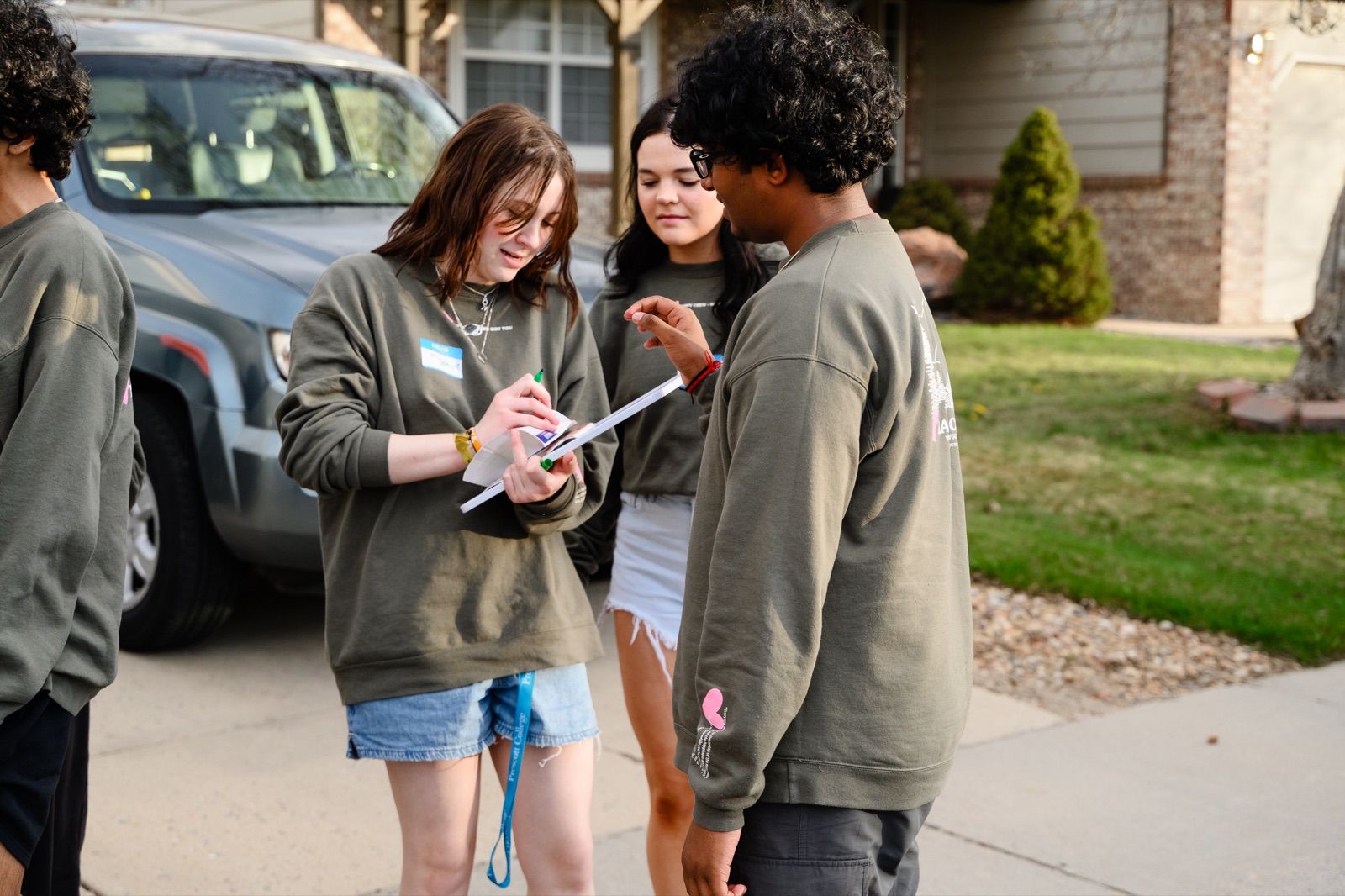Teens with name tags signing in on a clipboard