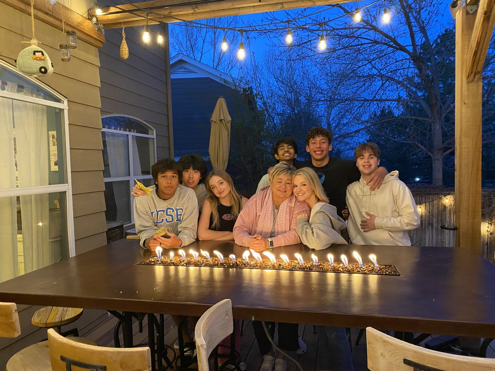 Amy Mays at her backyard table with teens on a Monday night, string lights overhead