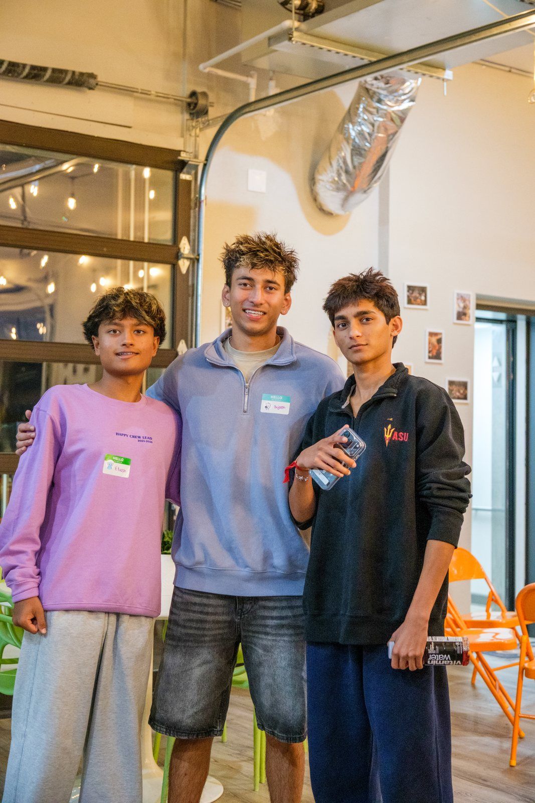 Three friends standing together upstairs, smiling