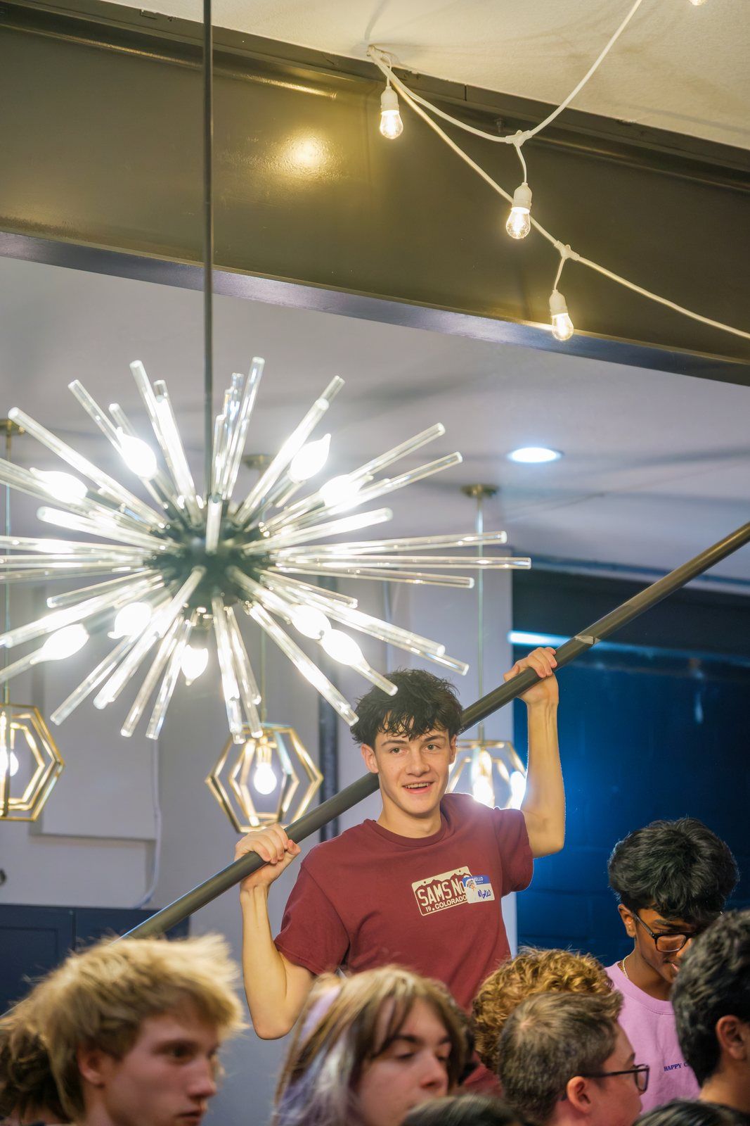 A teen reaching up by the starburst light, laughing