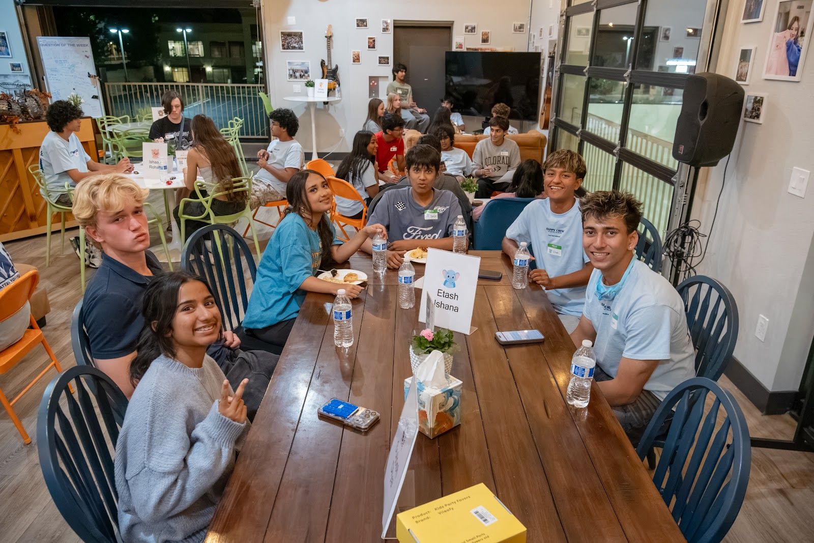 Teens at a long table at dinner, smiling at the camera