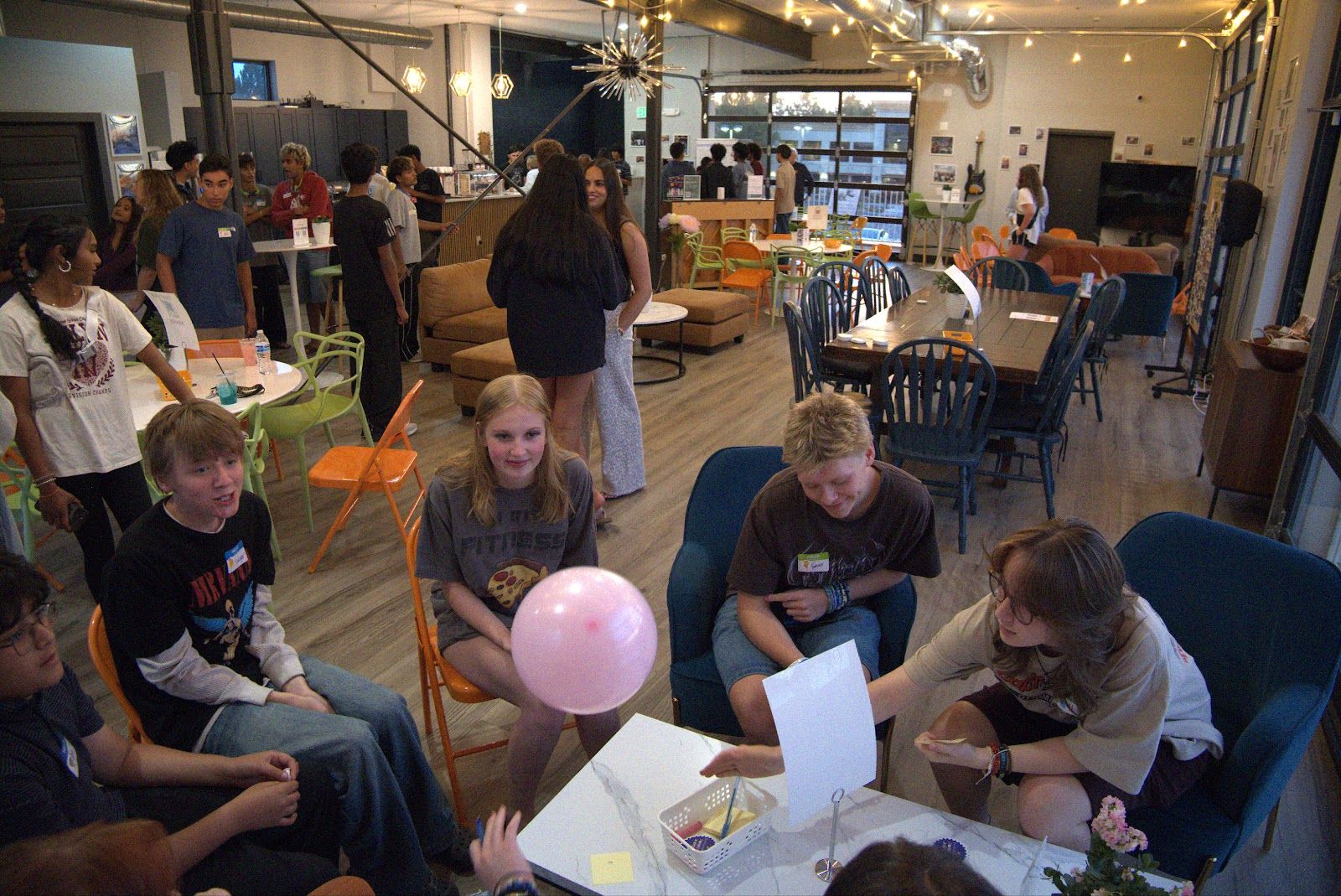 A small group of teens around a table, one holding a sheet of paper