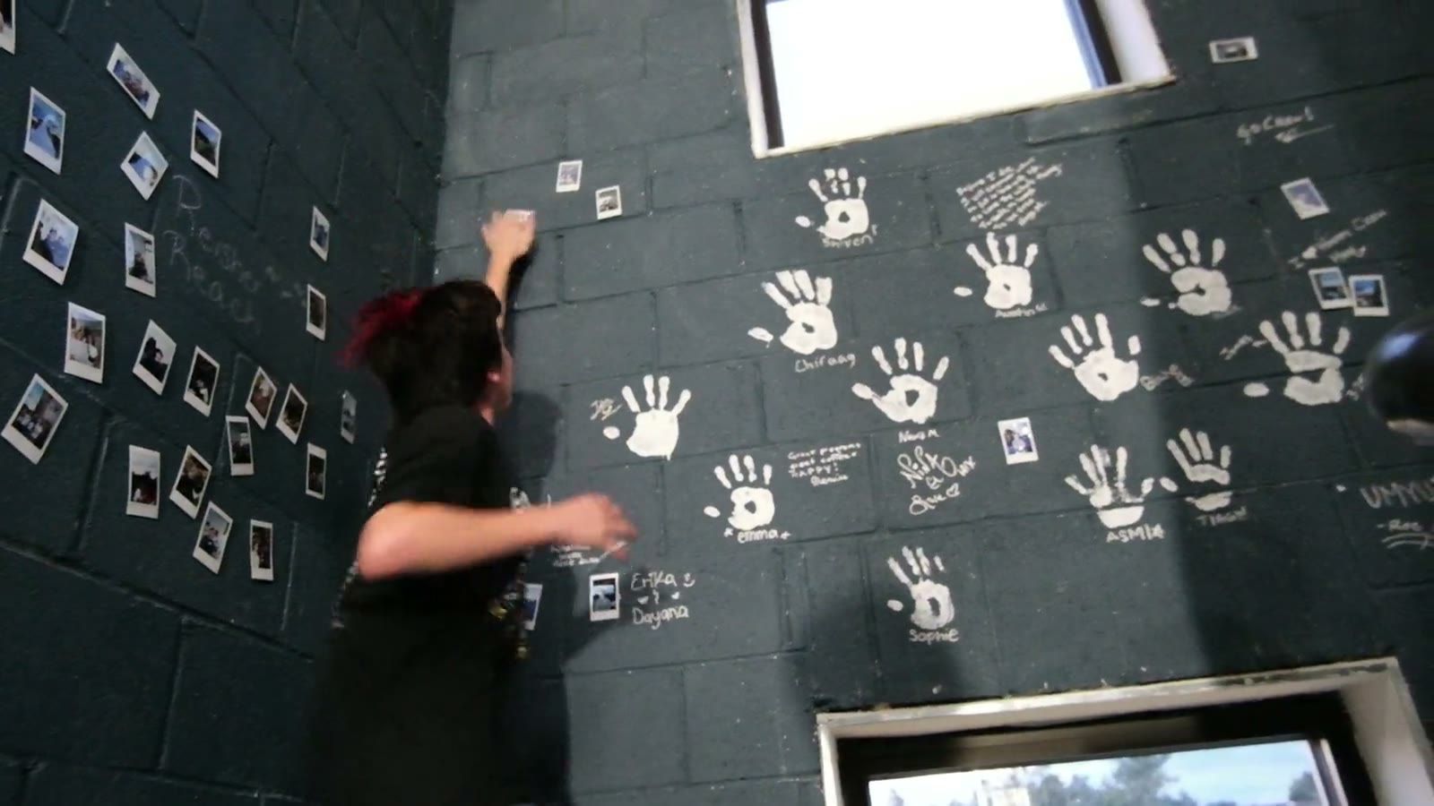 A teen pressing a handprint onto the wall at the top of the stairs