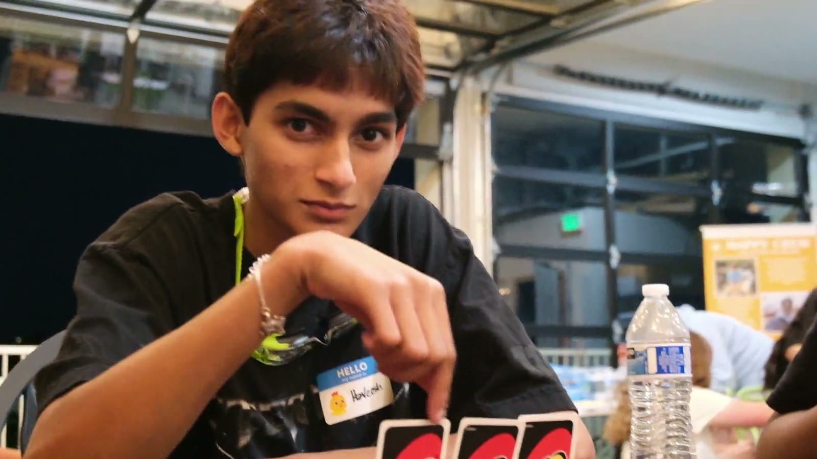 A teen holding Uno cards, looking at the camera